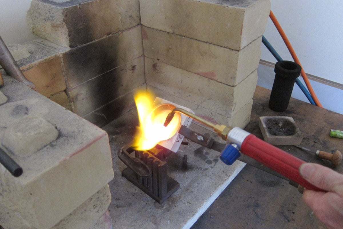 Gold grains are melted the liquid is poured into a mould to make a gold ingot.